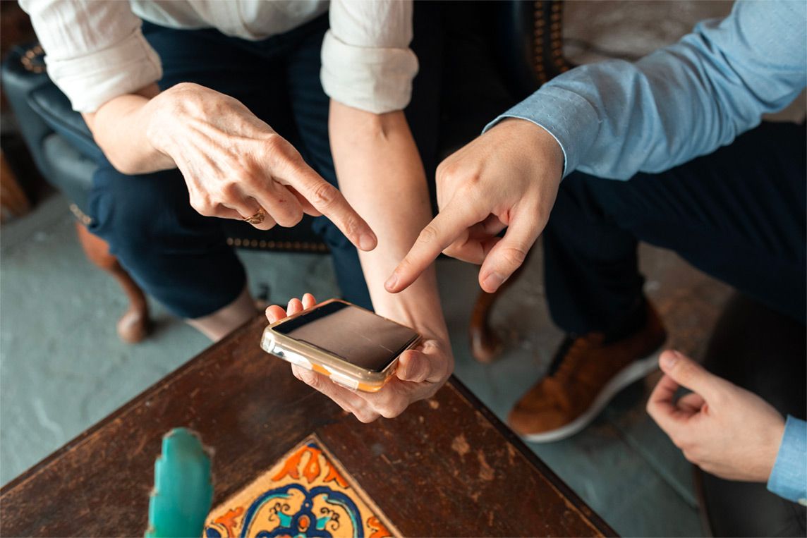 Photographie close-up sur des mains qui pointent un portable