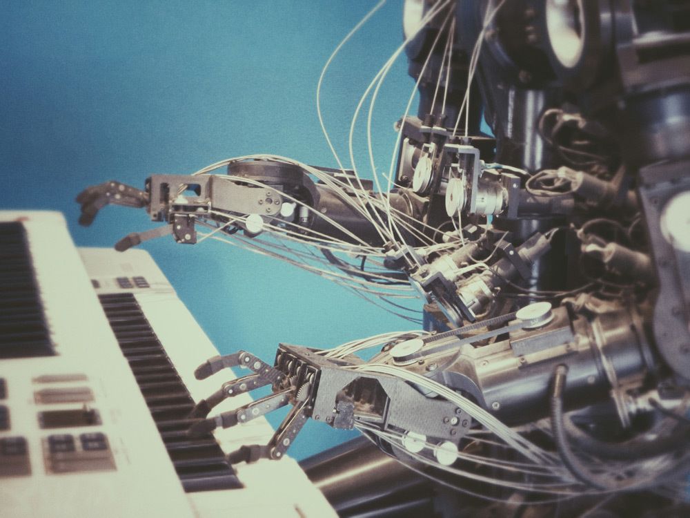 Robot jouant sur le clavier d'un piano. La caméra zoom sur ses mains et les touches du clavier. Le fond est bleu.